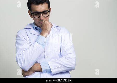 Studio shot der jungen schönen Indischen mann Arzt vor weißem Hintergrund Stockfoto