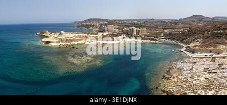 Blick aus der Vogelperspektive auf die Xwejni Bay in der Nähe von Zebbug, Gozo, mit türkisfarbenem Wasser, felsigem Kalksteinufer, Salinen und Gebäuden am Meer auf der Landzunge. Stockfoto