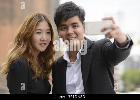 Porträt eines jungen asiatischen Geschäftsmannes und einer jungen asiatischen Geschäftsfrau zusammen in der Stadt draußen Stockfoto