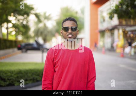 Porträt eines jungen gutaussehenden afrikanischen bärtigen Mannes mit Afro-Haaren, der die Straßen der Stadt im Freien erforscht Stockfoto