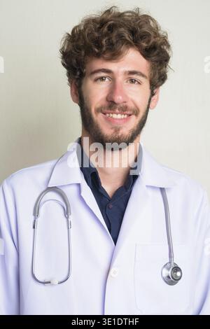 Studio-Aufnahme eines jungen gutaussehenden bärtigen Mannes Doktor mit lockigen Haaren vor weißem Hintergrund Stockfoto