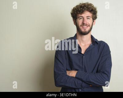 Studio-Aufnahme eines jungen gutaussehenden bärtigen Geschäftsmannes mit lockigen Haaren vor weißem Hintergrund Stockfoto