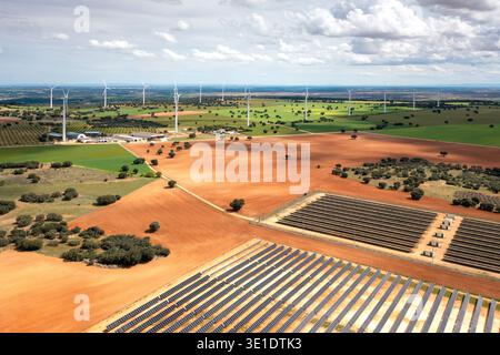 Drohnenaufnahme von Solar- und Windparks in weiten Feldern, die die Kombination von Solar- und Windenergie unter bewölktem Himmel hervorheben Stockfoto
