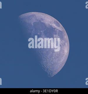 Ein hochauflösendes Nahfoto zeigt die detaillierte Oberfläche des Mondes vor einem tiefen, klaren blauen Himmel. Der Mond ist in einem abnehmenden Gaskern dargestellt Stockfoto