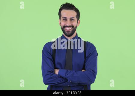 Studio-Aufnahme eines jungen gutaussehenden, bärtigen persischen Geschäftsmannes vor grünem Hintergrund Stockfoto