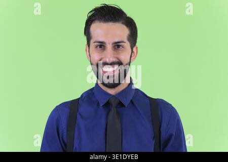 Studio-Aufnahme eines jungen gutaussehenden, bärtigen persischen Geschäftsmannes vor grünem Hintergrund Stockfoto