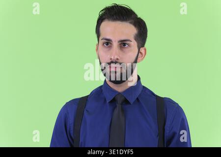Studio-Aufnahme eines jungen gutaussehenden, bärtigen persischen Geschäftsmannes vor grünem Hintergrund Stockfoto