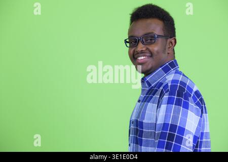 Studio shot junger afrikanischer hipster Mann mit Afro Haar zu tragen Brillen gegen grüner Hintergrund Stockfoto