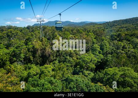 Eine Gondel und ein Stützturm der Skyrail Rainforest Cableway über dem dichten tropischen Regenwald mit Blick auf die Berge in der Nähe von Cairns, Australien. Stockfoto