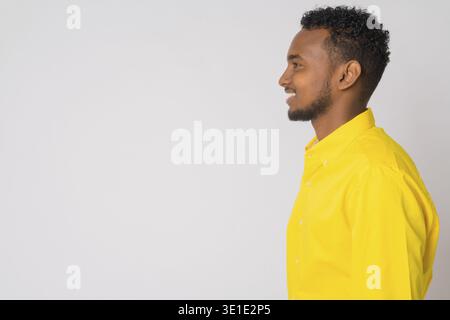 Studio shot der jungen schönen afrikanischen Geschäftsmann tragen gelbe Shirt vor weißem Hintergrund Stockfoto
