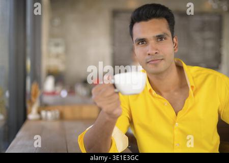 Porträt eines hübschen Indianers, der im Café sitzt Stockfoto