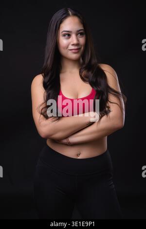 Studio-Aufnahme einer jungen, schönen Multi-Ethno-Frau, die für das Fitnessstudio bereit ist, vor schwarzem Hintergrund Stockfoto