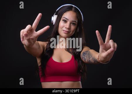 Studio-Aufnahme einer jungen, schönen Multi-Ethno-Frau, die für das Fitnessstudio bereit ist, vor schwarzem Hintergrund Stockfoto