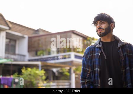 Porträt eines jungen gutaussehenden bärtigen indischen Hipster-Mannes auf der Straße draußen Stockfoto