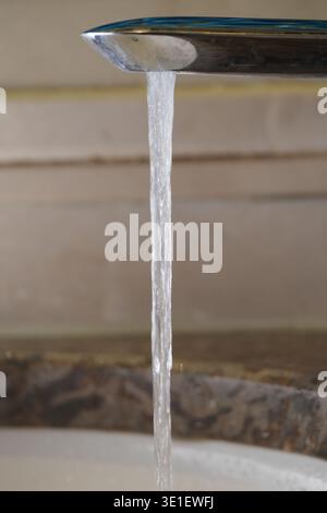 Wasser fließt aus einem Wasserhahn in einem Waschbecken in einem Haus Stockfoto