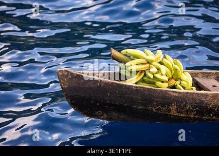 Ein mit Bananen gefülltes Kanu schwimmt auf dem tiefblauen Wasser. Stockfoto