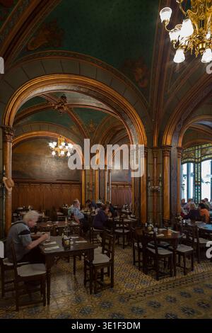 Gäste können in einem prunkvollen neogotischen Speisesaal mit vergoldeten Bögen, bemalter Decke und Mosaikboden im Caru cu Bere, Bukarest, Rumänien, speisen Stockfoto