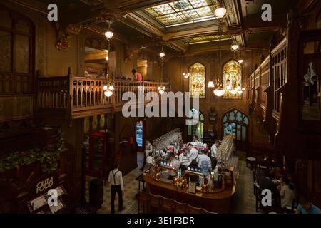 Verzierte Innenausstattung der historischen Bierhalle Caru cu Bere mit Buntglasfenstern und geschnitztem Holzbalkon, Bukarest, Rumänien Stockfoto