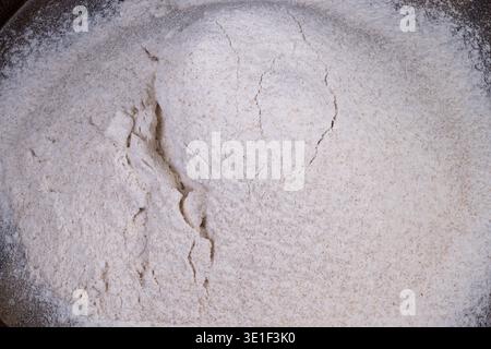 Vollkornmehlhügel für gesundes Backen, grobe Textur mit sichtbaren Kleieflecken auf Holztablett, gesunde rustikale Atmosphäre, nahrhafte Zutat Stockfoto
