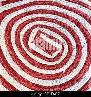 Ein rot-weißes geometrisches Spiralmuster ist Teil eines gewebten Korbs. Stockfoto