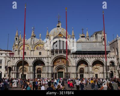 Markusdom mit Menschenmassen an der Piazza San Marco in Venedig, Italien inmitten der historischen venezianischen Architektur. Stockfoto