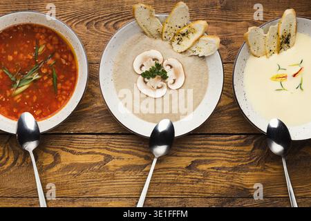 Set mit verschiedenen Suppen auf hölzernem Hintergrund, Blick von oben Stockfoto
