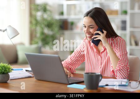 Glückliche Selbstständige, die zu Hause online arbeiten, um Telefongespräche zu führen Stockfoto