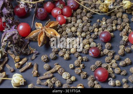 Verschiedene Gewürze auf dunklem Hintergrund mit Gräsern, Lorbeerblättern, Beeren und anderen Gewürzen zum Kochen duftender Ost- und Mittelweste Stockfoto