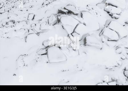 Aus der Vogelperspektive auf eine schneebedeckte Landschaft, in der zerklüftete Felsen mit weiß bedeckt sind, was einen starken Kontrast zwischen Licht und Schatten schafft, Senjahopen, Tro Stockfoto