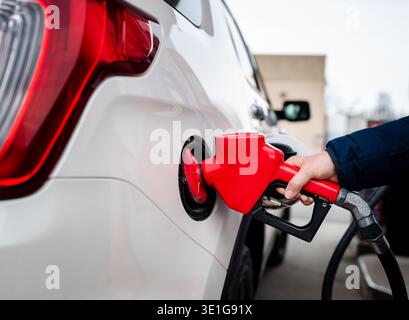 Nahaufnahme der Hand an der Kraftstoffdüse, die den Tank des Fahrzeugs mit Gas füllt. Stockfoto