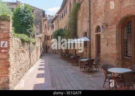 Leere enge Straße in einer historischen europäischen Stadt mit Cafés im Freien. Steinmauern, warme Töne und ruhige morgendliche Atmosphäre. Reisen, Architektur Stockfoto