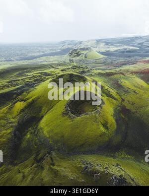 Aus der Vogelperspektive der grünen Vulkankrater wird die krasse, moosbedeckte Landschaft durchbrochen und ein surreales Wandteppich aus Texturen und Tönen geschaffen, Skaftárhreppur Stockfoto