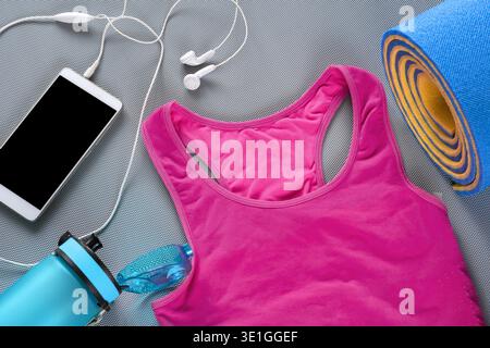 Stilvolle Fitnessaccessoires wie Yogamatte, Sportbekleidung und digitale Musikausrüstung sorgen für eine gesunde morgendliche Fitness-Routine Stockfoto
