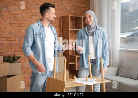 Glückliches muslimisches Paar, das zu Hause Regale zusammenbaut Stockfoto