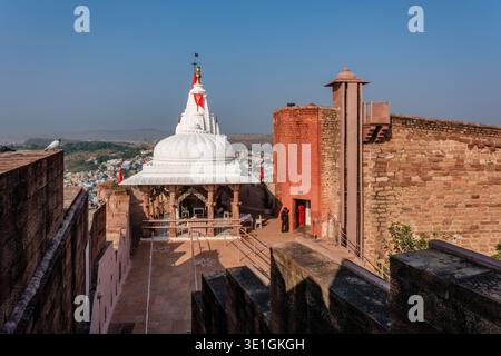 Der Chamunda Mataji Tempel im Mehrangarh Fort in Jodhpur überblickt die Blaue Stadt in der Ferne mit ihren charakteristischen weißen Kuppeln und Fahnen. Stockfoto