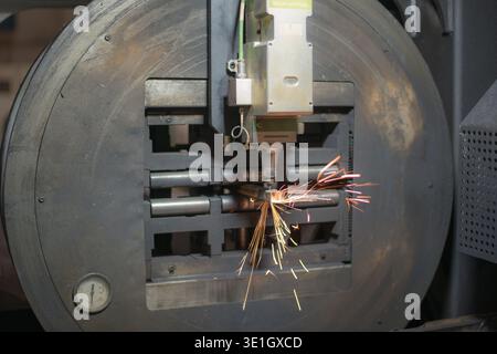 Laser-Rohrschneider im Betrieb. Der Laserkopf brennt durch das Metallprofil und wirft Funken. Hochwertige Fotos Stockfoto