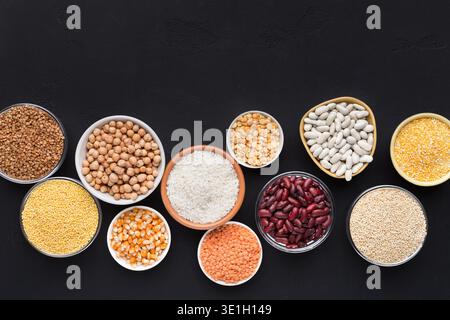 Hülsenfrüchte und Körner in verschiedenen Schüsseln auf schwarzem Hintergrund Stockfoto