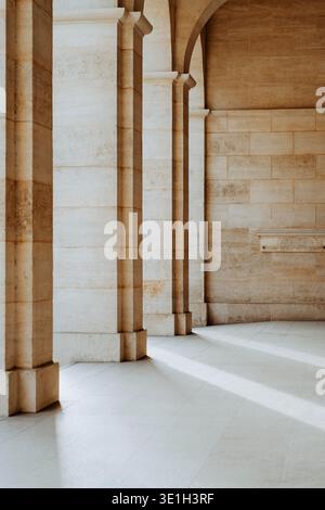 Minimalistische Architekturszene mit eleganten Steinsäulen und weichem natürlichem Licht, das geometrische Schatten schafft. Ruhige klassische europäische Architektur mit Stockfoto