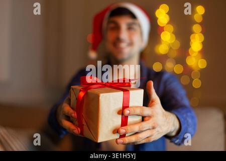 Ein Mann, der weihnachtsgeschenk gibt, weihnachtsmütze trägt Stockfoto
