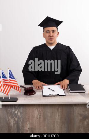 Richter in schwarzem Gewand, der sich die Dokumente auf dem Schreibtisch ansieht Stockfoto