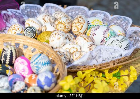 Nahaufnahme eines Korbkörpers mit bunten handbemalten Ostereiern, die mit traditionellen Mustern dekoriert sind, Eier sind auf festlichem Tisch angeordnet Stockfoto