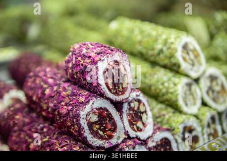 Schöner Hintergrund mit roten und grünen Süßwaren. Nationalgericht Türkische Köstlichkeiten mit weißem Nougat, heller Mischung Füllung in der Mitte, Nüssen und che Stockfoto