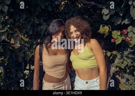Porträt zweier junger Frauen, die an einem sonnigen Sommertag im Freien zusammen lächeln. Stockfoto