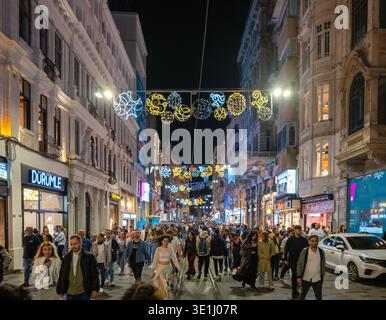 Eine geschäftige Fußgängerzone voller Menschen, die unter farbenfrohen runden Lichtdekorationen laufen, die über dem Kopf hängen. Taksim, Beyoglu, Istanbul, Türkei Stockfoto