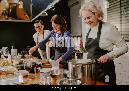 Gruppe von Frauen und Männern mittleren Alters, die gemeinsam am Kochkurs teilnehmen Stockfoto