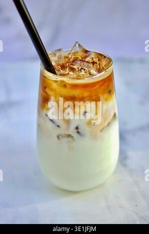 Milchshake Eiskaffee mit Eis in einem hohen Glasglas mit Strohhalm auf hellem Marmorhintergrund Stockfoto