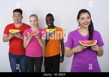 Studio shot der glücklichen jungen indischen Frau mit vielfältigen Gruppe von multi-ethnische Freunde lächelnd, während sie ein Stück Wassermelone zusammen Stockfoto