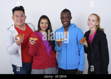 Studio shot von Happy vielfältige Gruppe von multi-ethnische Freunde lächelnd, während sie Stück Pizza zusammen Stockfoto