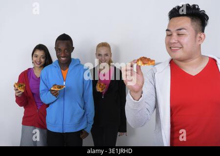 Studio shot der glücklichen jungen asiatischen Mann am Stück Pizza mit vielfältigen Gruppe von multi-ethnische Freunde und lächelnd Stück Pizza zusammen Stockfoto