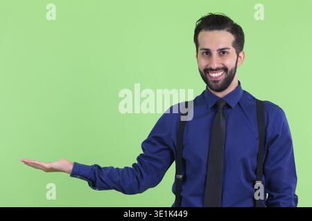 Studio-Aufnahme eines jungen gutaussehenden, bärtigen persischen Geschäftsmannes vor grünem Hintergrund Stockfoto